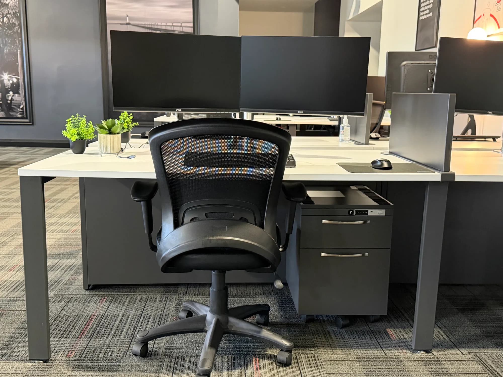 A dedicated desk with two monitors and a personal locked cabinet