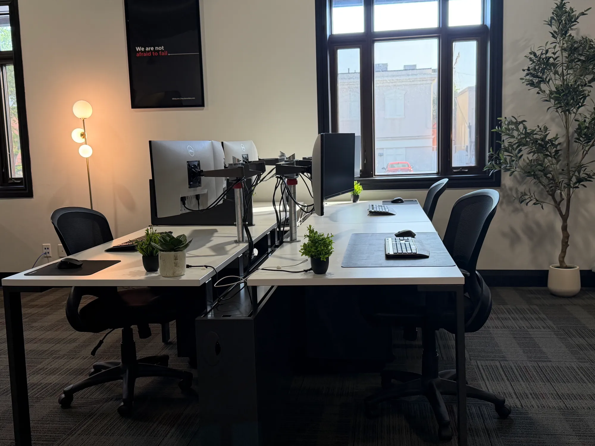 Dedicated desks with dual monitors and mesh chairs in the open area